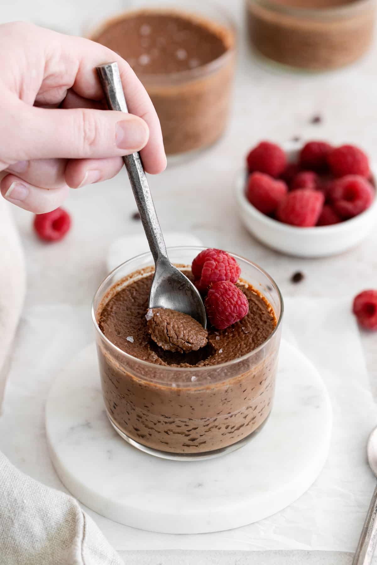 hand dipping into pot de creme with a dessert spoon