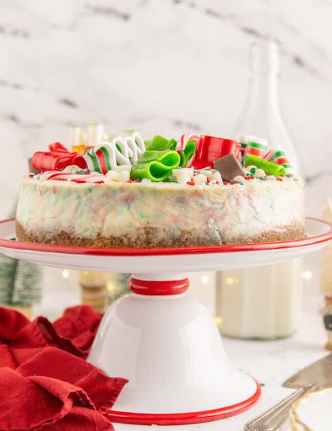 christmas cheesecake on a red and white cake stand.