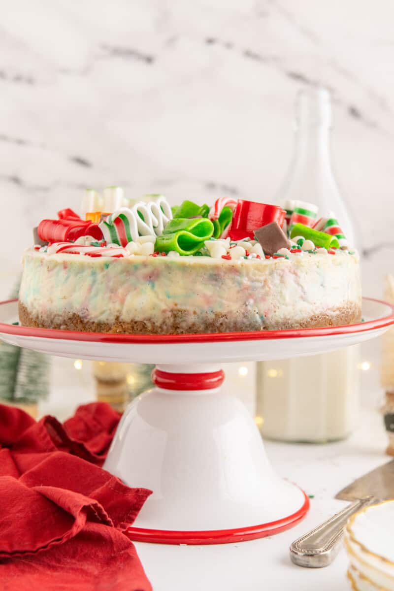 christmas cheesecake on a red and white cake stand.