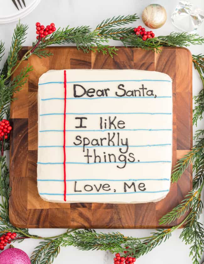overhead view of letter to santa cake with the message dear santa, I like sparkly things love, me on a wooden cutting board.