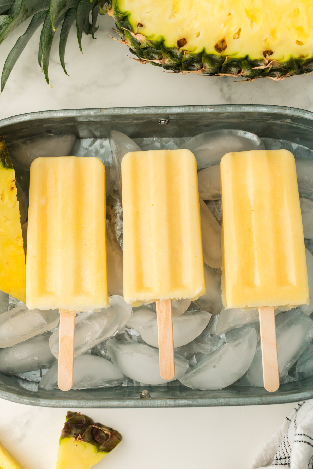 pineapple dole whip popsicles laid in a bucket of ice