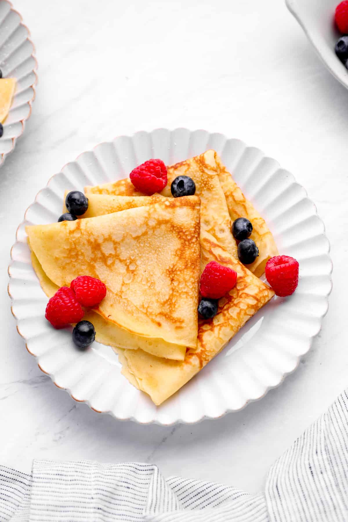 a plate of easy crepes, folded with berries