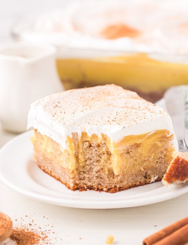 a partially eaten slice of eggnog poke cake on a white plate.