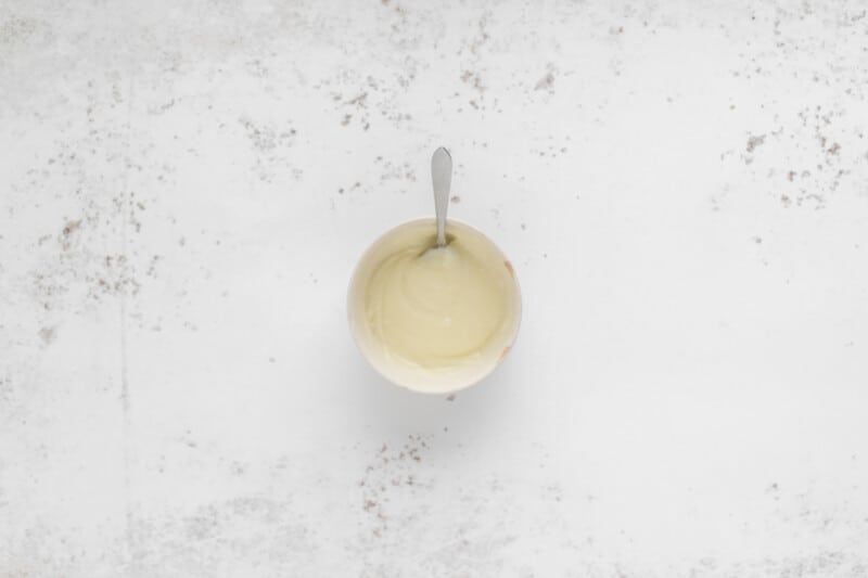 white chocolate ganache in a white bowl with a spoon.