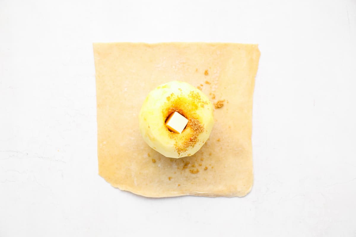 an apple stuffed with cinnamon sugar and butter on a square of pie crust.