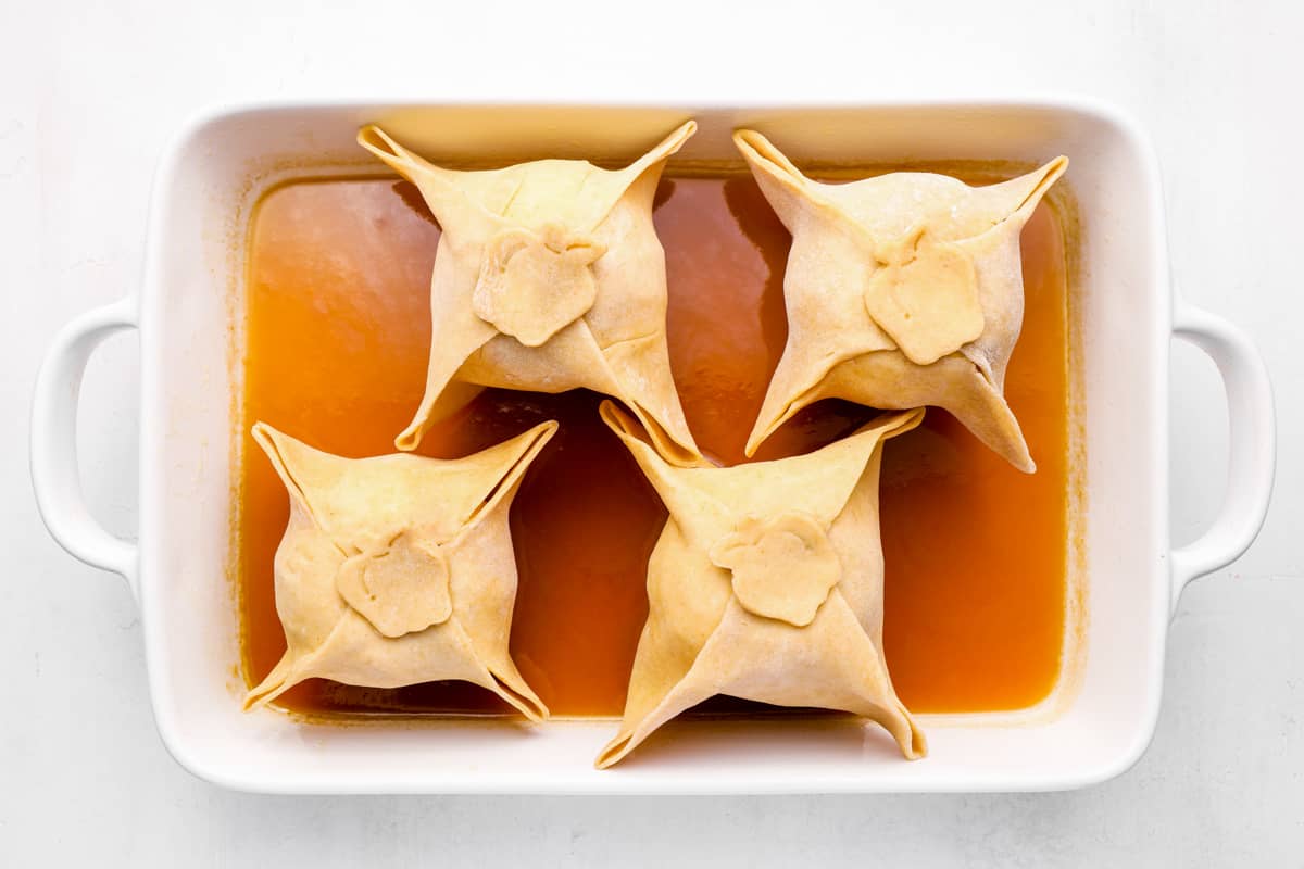 apple dumplings in a baking pan with sauce.