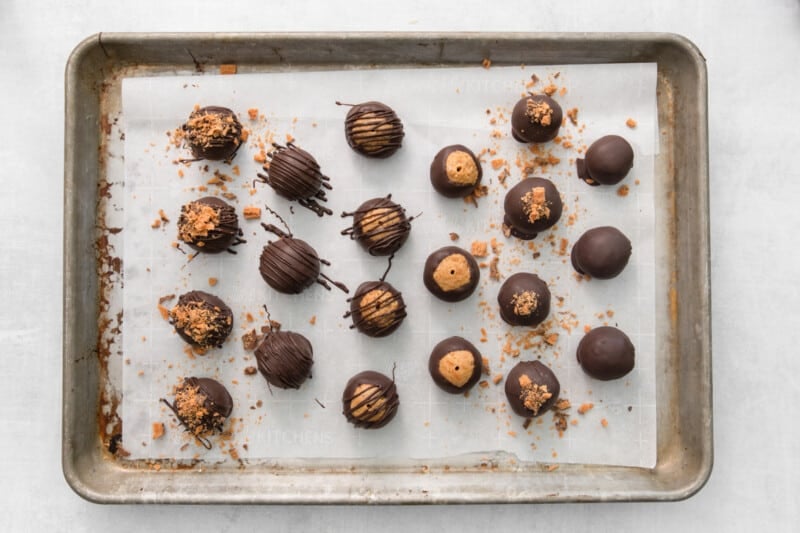 21 chocolate dipped butterfinger balls on a baking sheet.