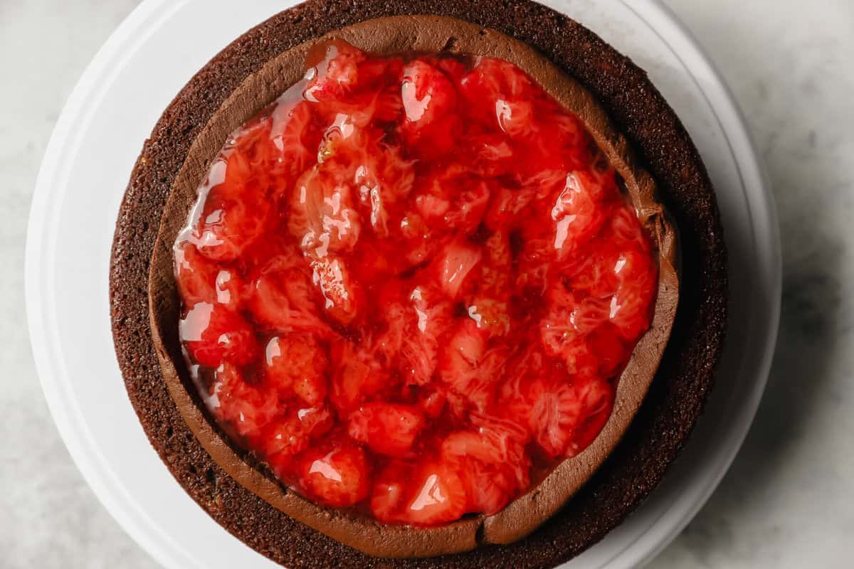 a layer of chocolate cake topped with a ring of frosting and filled with strawberry filling.