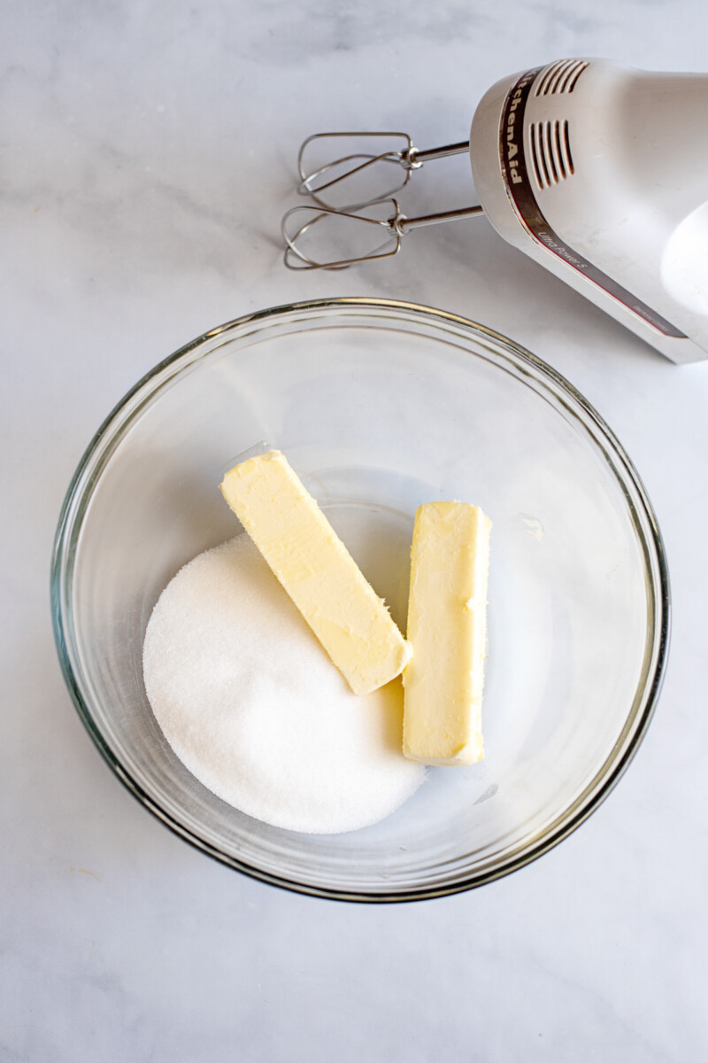 sticks of butter and sugar in a mixing bowl, before creaming