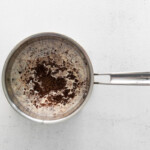 a frying pan with coffee in it on a white background.