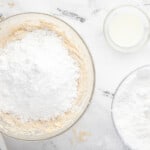 a bowl of flour, sugar, and other ingredients on a marble countertop.