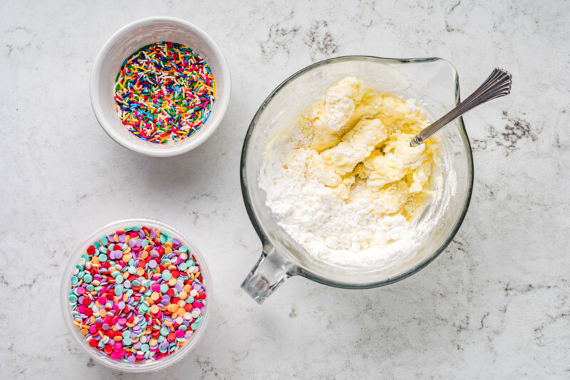 a bowl of powdered sugar, a bowl of flour, and a bowl of sprinkles.