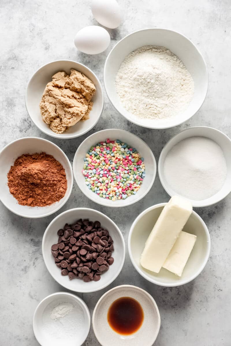 overhead view of ingredients for cosmic brownie cookies in white bowls.