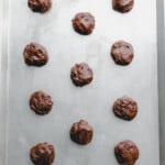 11 cosmic brownie cookie dough balls on a baking sheet.