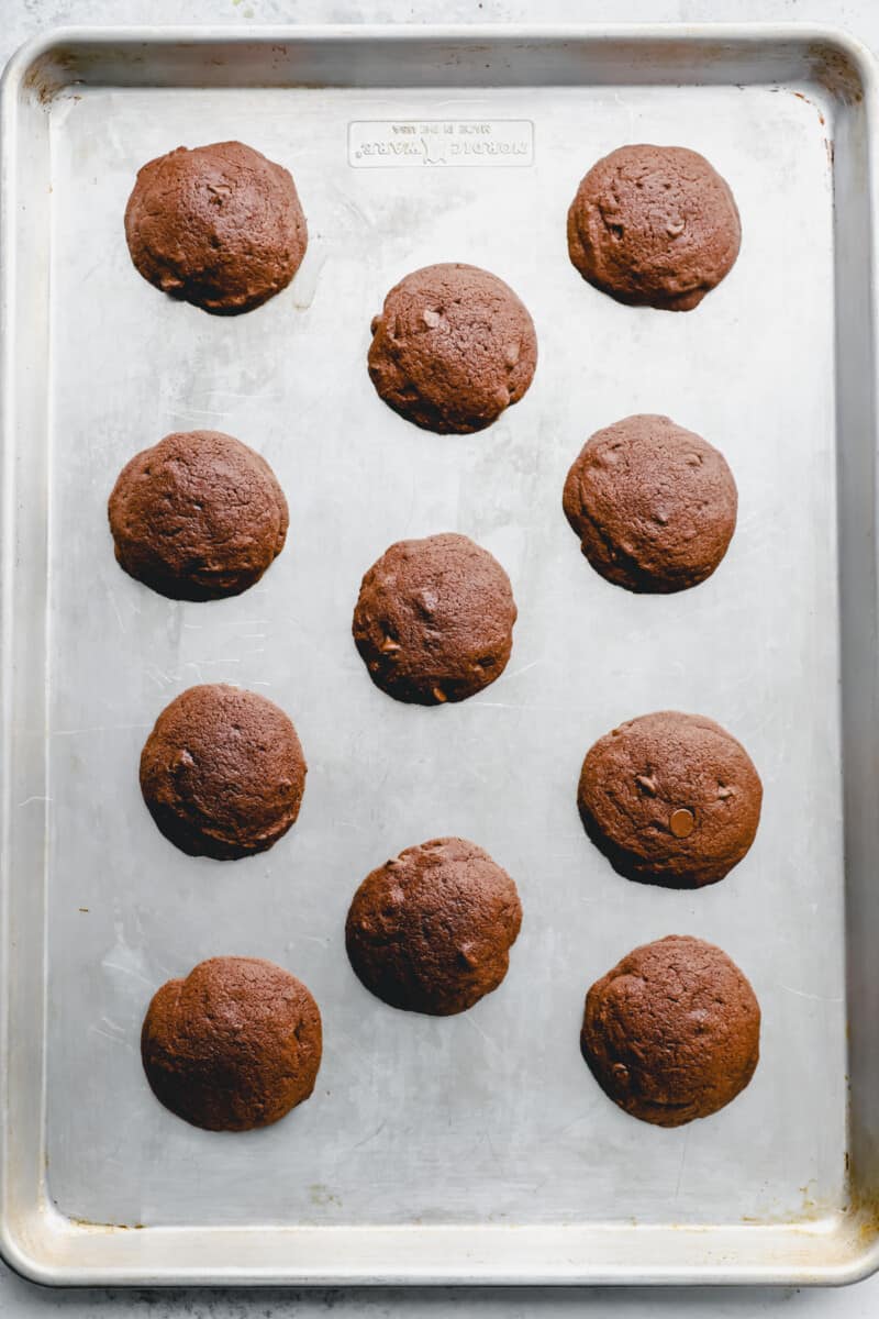 11 baked cosmic brownie cookies on a baking sheet.