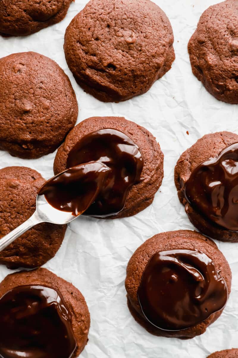 a spoon drizzling ganache over cosmic brownie cookies.