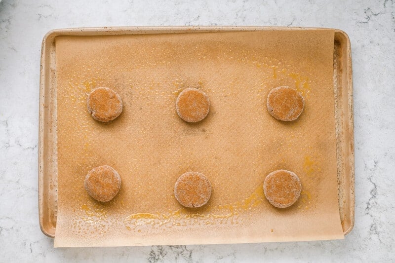 6 frosted gingerbread cookie dough balls on a baking sheet.