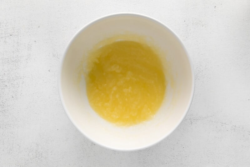 a bowl of yellow liquid on a white surface.
