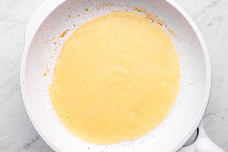 a frying pan with a yellow batter in it.