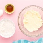 a bowl of butter, eggs and sugar on a pink background.