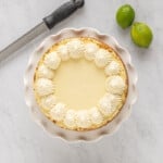 a white cake with whipped cream and limes on top.