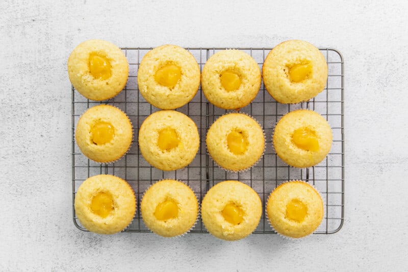 cupcakes filled with lemon curd, lined up on a cooling rack