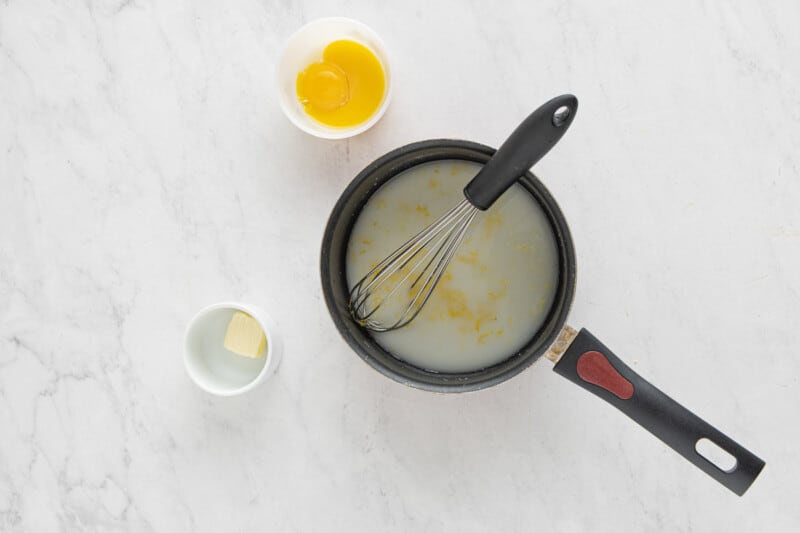 a frying pan with eggs and butter on a marble table.
