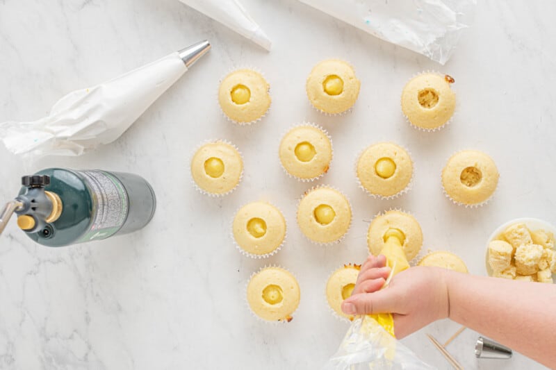 a child is putting yellow cupcakes on a table.