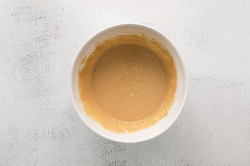 a bowl of peanut butter on a white surface.