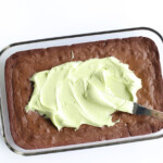 spreading mint frosting on top of baked brownies
