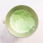 green icing in a bowl on a white background.