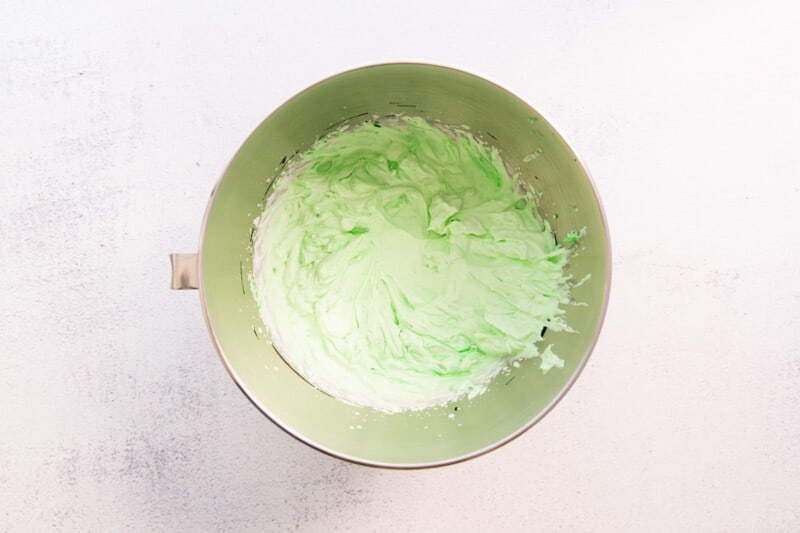 green icing in a bowl on a white background.