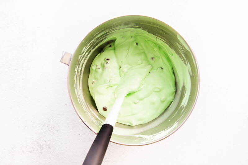 mixing mint chocolate chip ice cream in a mixing bowl with a spatula