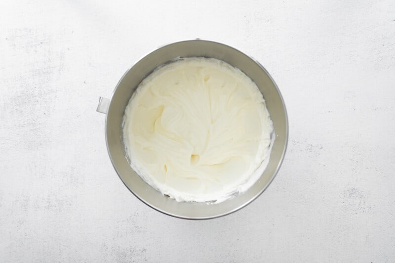 whipped cream in a metal bowl on a white background.