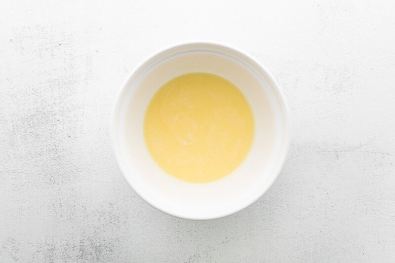 a bowl of yellow liquid on a white background.