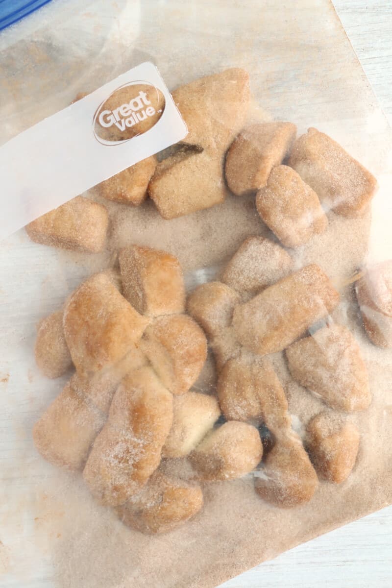 pieces of dough inside of a resealable bag, mixing with cinnamon sugar