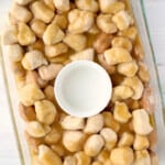 a glass baking dish filled with nuts and caramel.