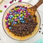 mixing chocolate chips and m&ms into batter