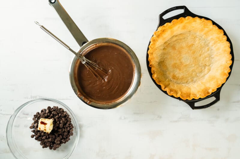a chocolate pie with chocolate chips and a whisk next to it.
