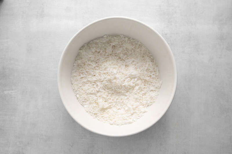 shredded coconut mixed with powdered sugar in a white bowl.