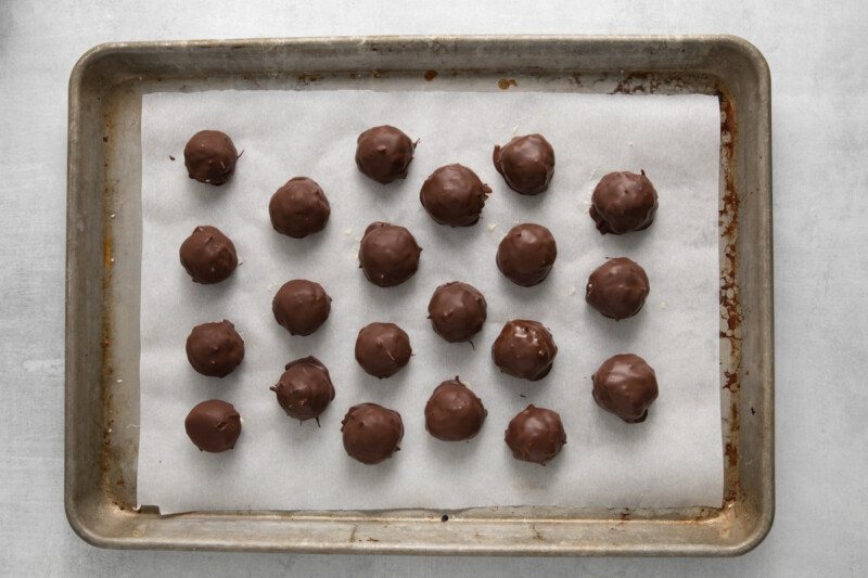 21 coconut truffles on a baking sheet.