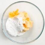 a bowl of flour, butter, and sugar on a white background.