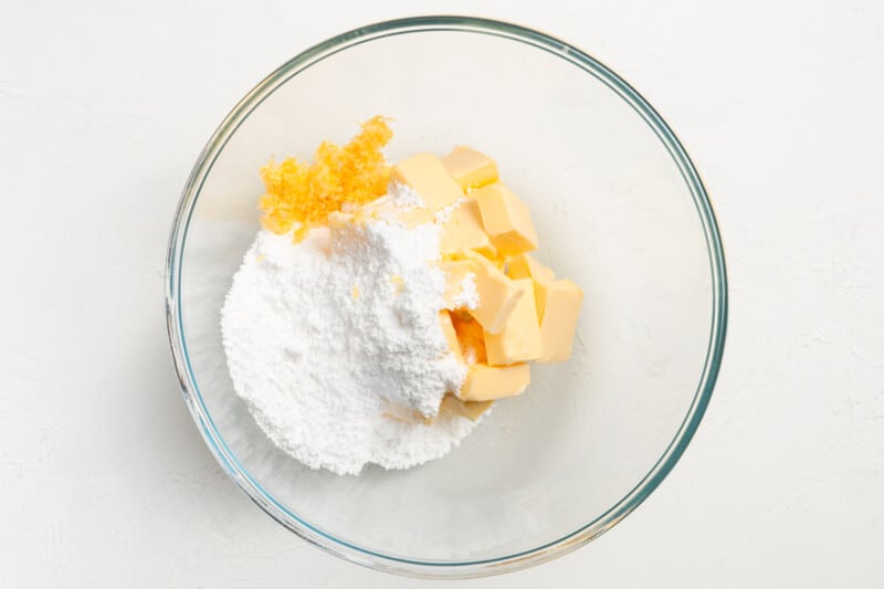 a bowl of flour, butter, and sugar on a white background.