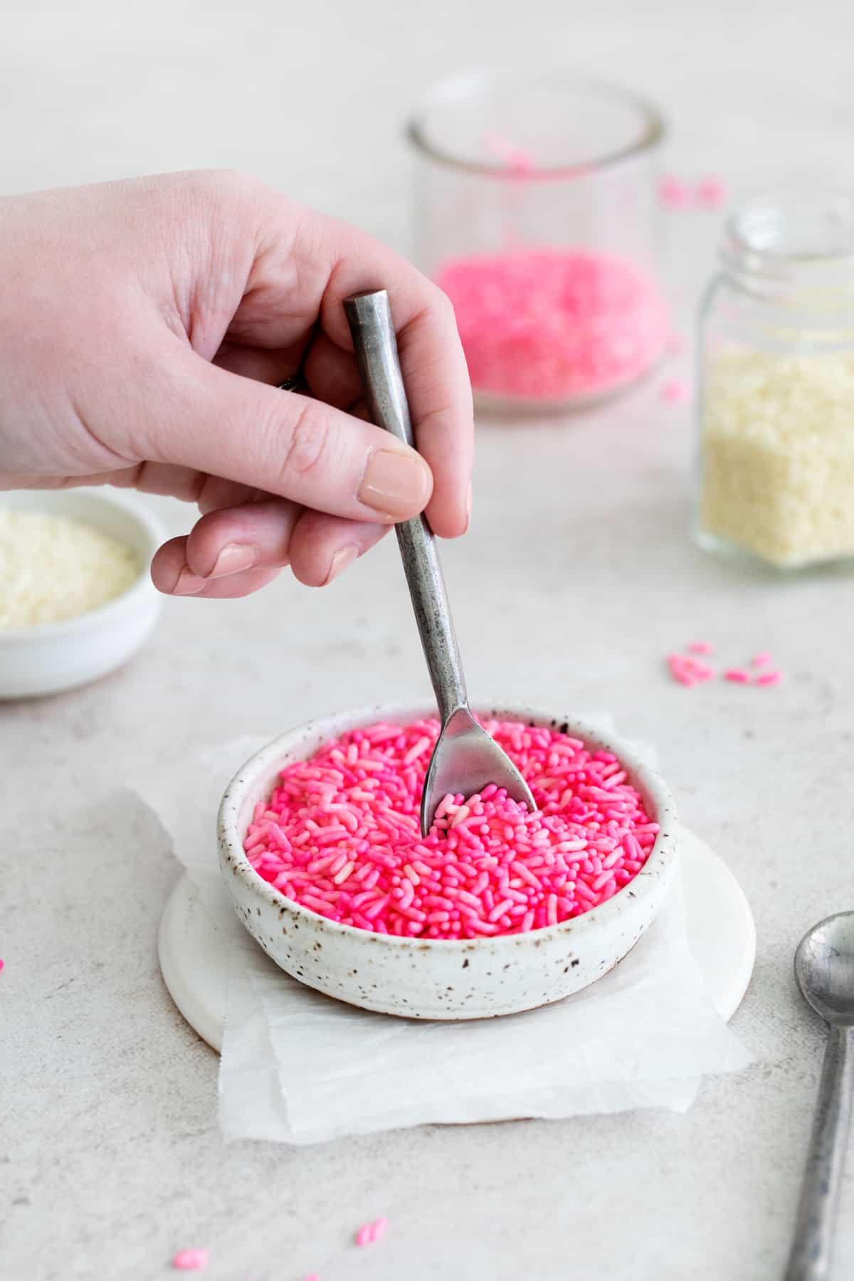 digging into a bowl of colored sprinkles with a small spoon