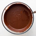 overhead view of melted chocolate in a glass bowl with a spoon.