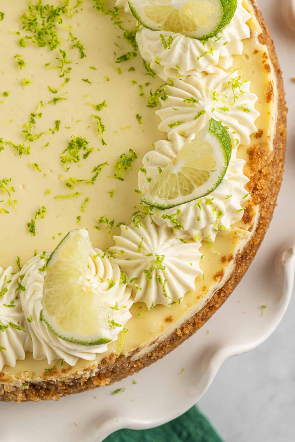 close up on the top of a key lime cheesecake, garnished with lime slices and zest