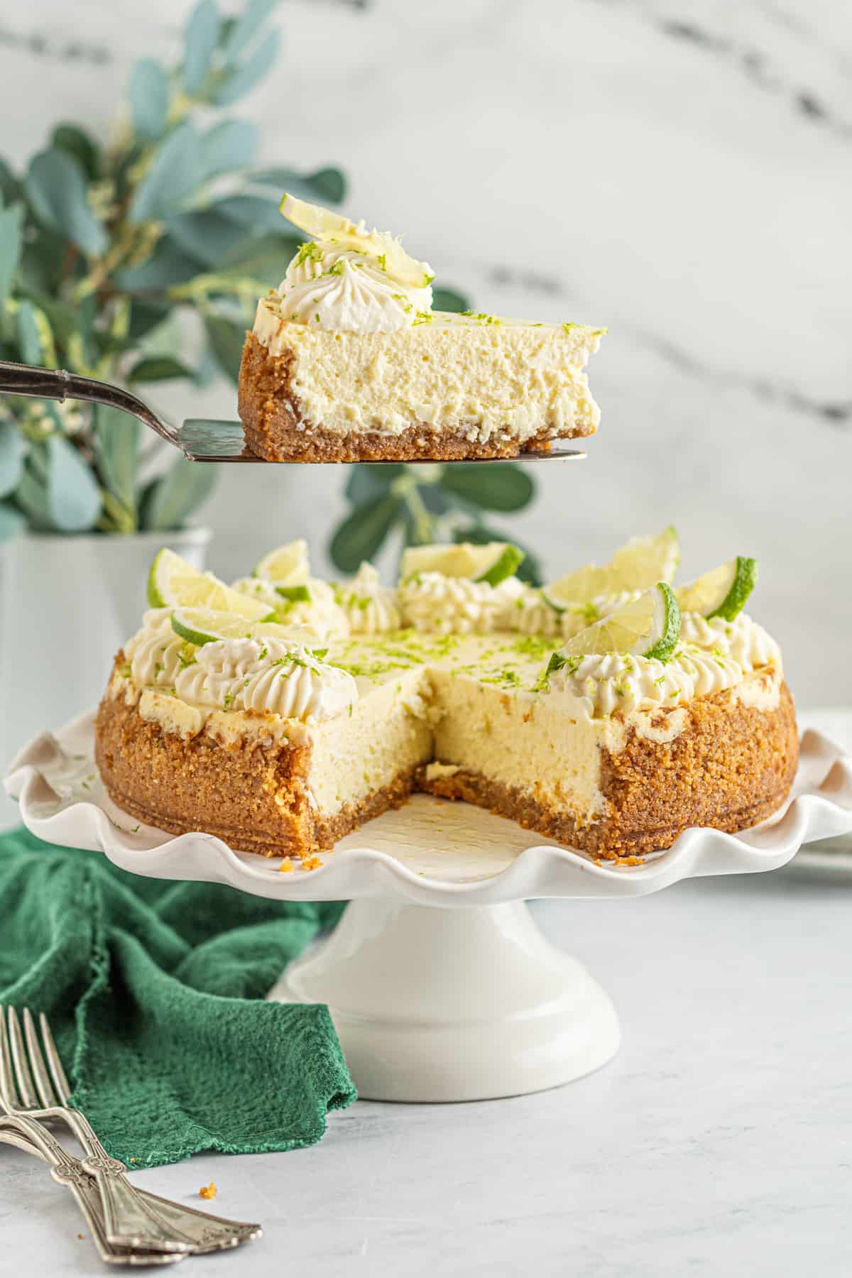 key lime cheesecake on a cake stand, one slice being removed