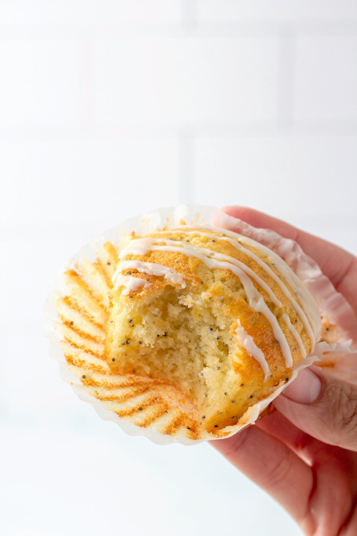 hand golding up a lemon poppy seed muffin with a bite taken out of the front