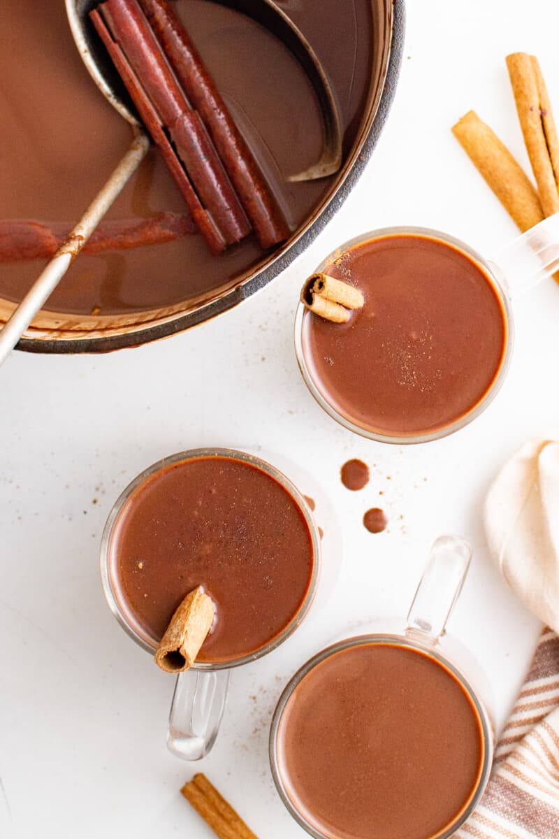 overhead view of mugs of meixcan hot chocolate with cinnamon sticks.