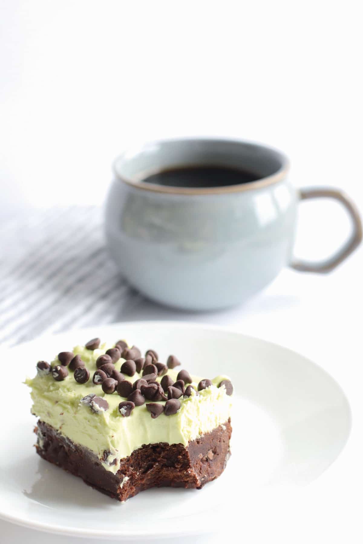 mint chocolate chip brownie on a plate with a cup of coffee